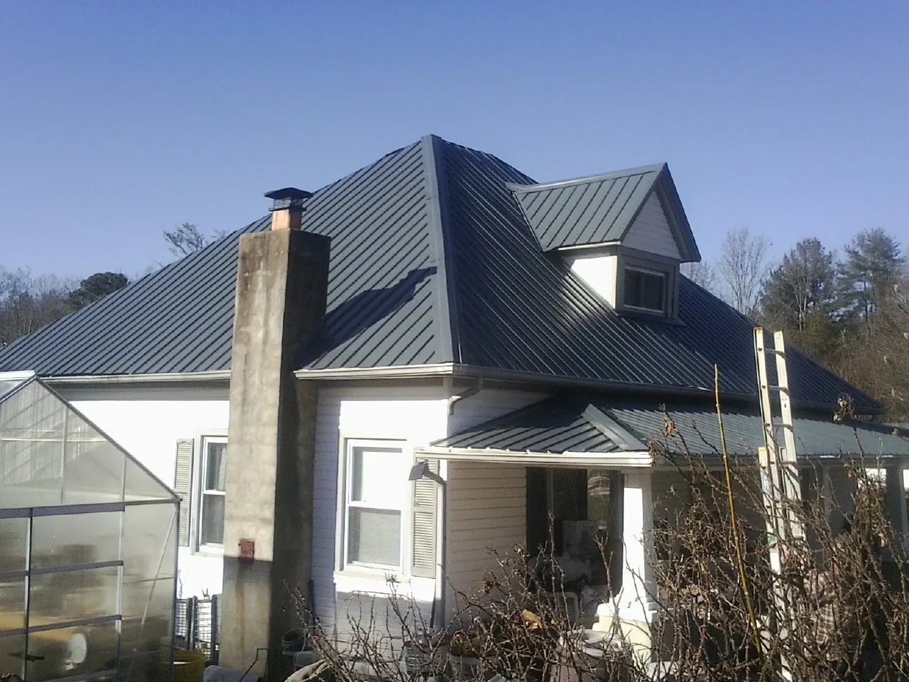 Dark blue standing seam metal roof on a white farmhouse with dormer — Slate & Tile Roof Repair by Roofing Brothers in Fultonham