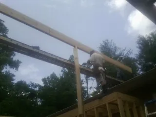 Carpenter setting a ridge beam over a new addition frame — Ice Dam Removal by Roofing Brothers in Fultonham