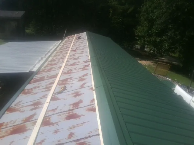 Old rusted panels beside newly installed green metal roofing — Wind Damage Roof Repair by Roofing Brothers in Fultonham