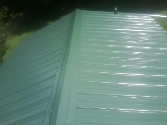 New green metal panels meeting at the ridge of a roof — Flat Roof Repair work by our crew in Fultonham