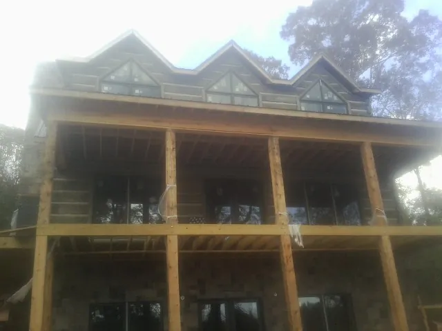 Dormers and porch framing on a large log home under construction — Roof Coating work by our crew in Fultonham