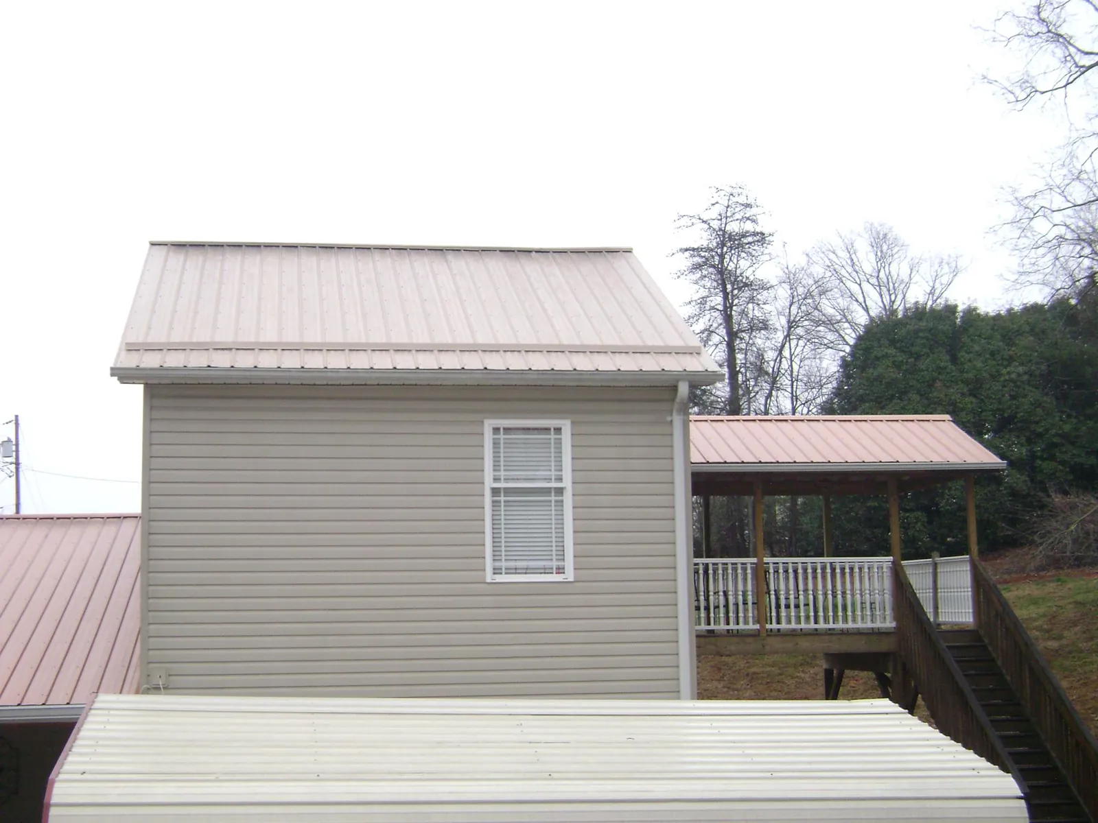 Tan metal roofs on a two story addition and attached porch, from a Roof Replacement job in Fultonham