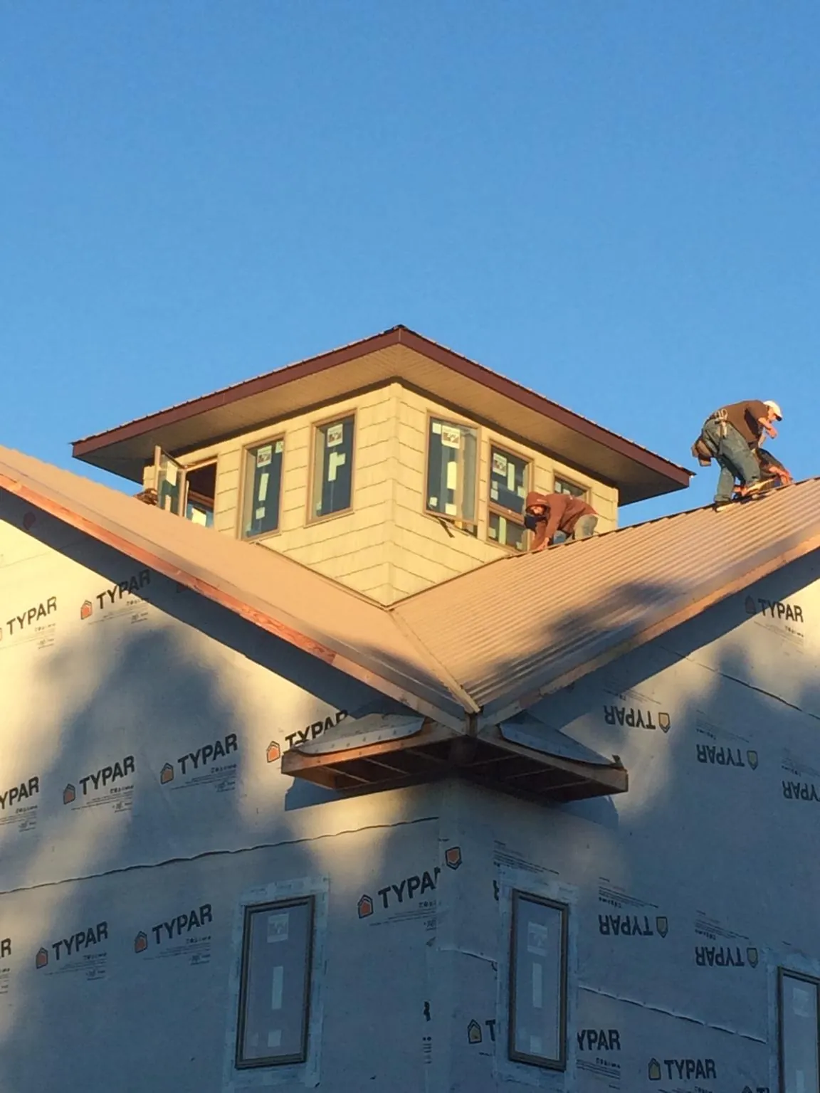 Roofers working around a rooftop cupola on a new metal roof at sunset — Roof Waterproofing in Fultonham by Roofing Brothers